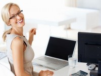 Portrait of smiling young business woman at office desk with laptop