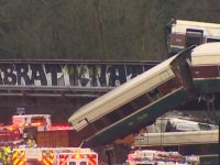 В США пассажирский поезд рухнул с моста на автомагистраль, много пострадавших