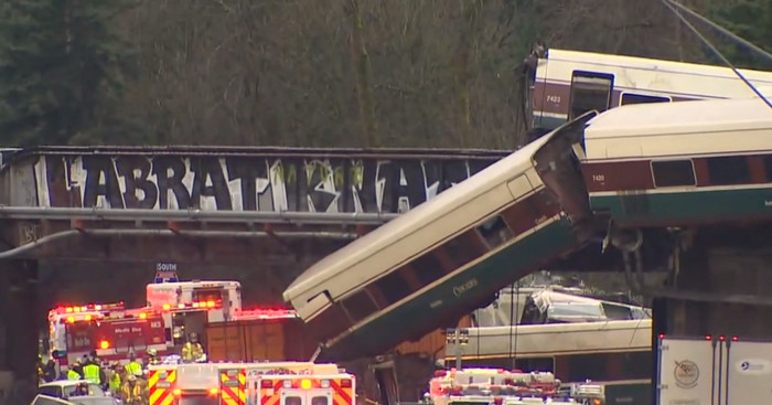 В США пассажирский поезд рухнул с моста на автомагистраль, много пострадавших